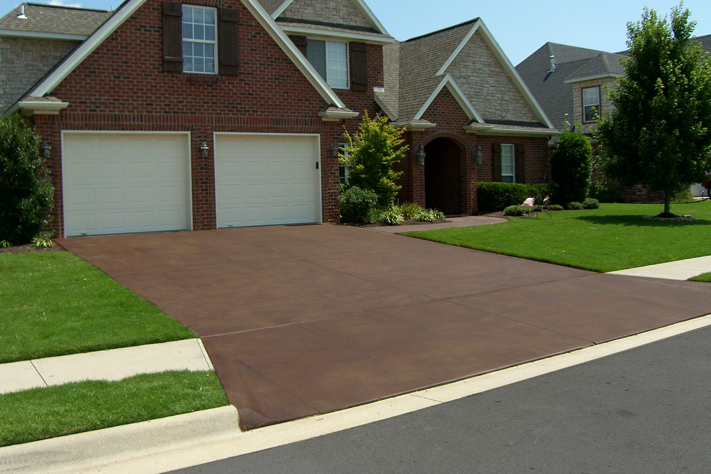 a brick-red driveway finish in front of a two-car garage